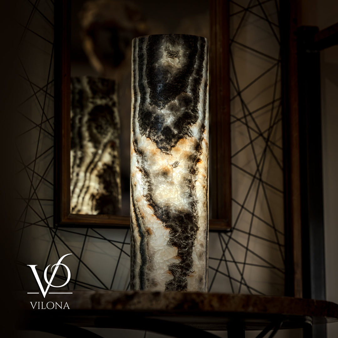 Onyx table lamp base centered on table, dark top and cream veining; cord trailing.