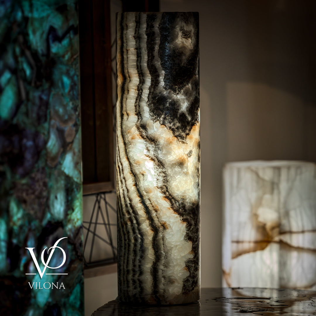 Tall onyx table lamp base with dark top and cream swirls; curved surface texture.
