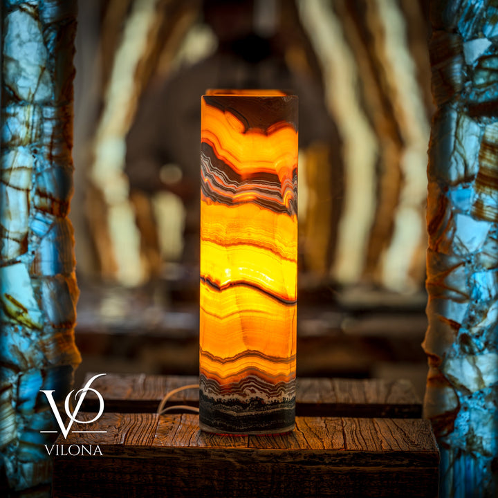 Onyx cylinder table lamp with orange-yellow glow and dark banded stone layers
