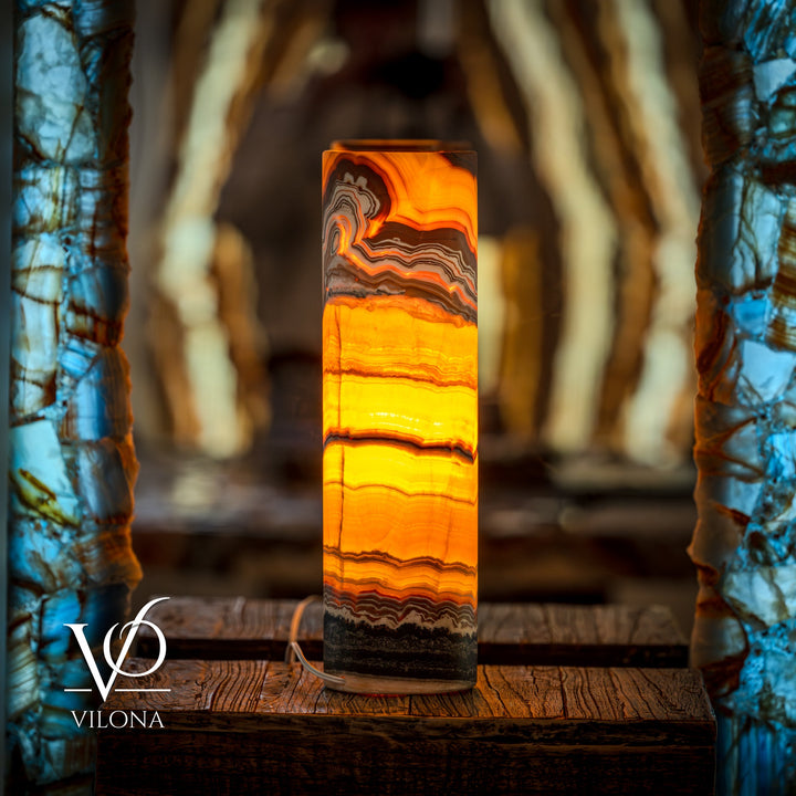 Onyx cylinder table lamp with bright orange glow and wavy striped stone pattern