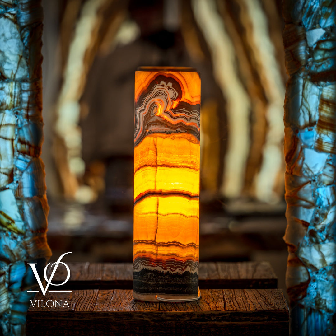 Onyx cylinder table lamp emitting warm orange light with dark bottom band