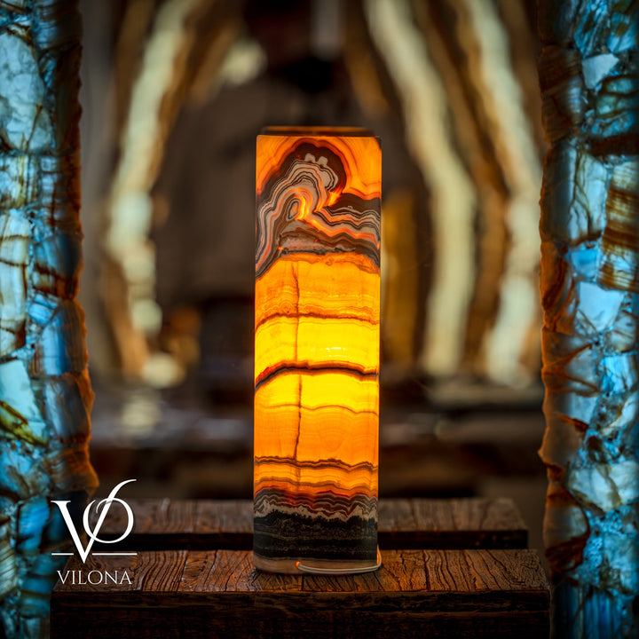 Onyx cylinder table lamp emitting warm orange light with dark bottom band