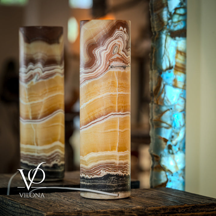 Onyx cylinder table lamp with soft golden glow and layered cream stone stripes