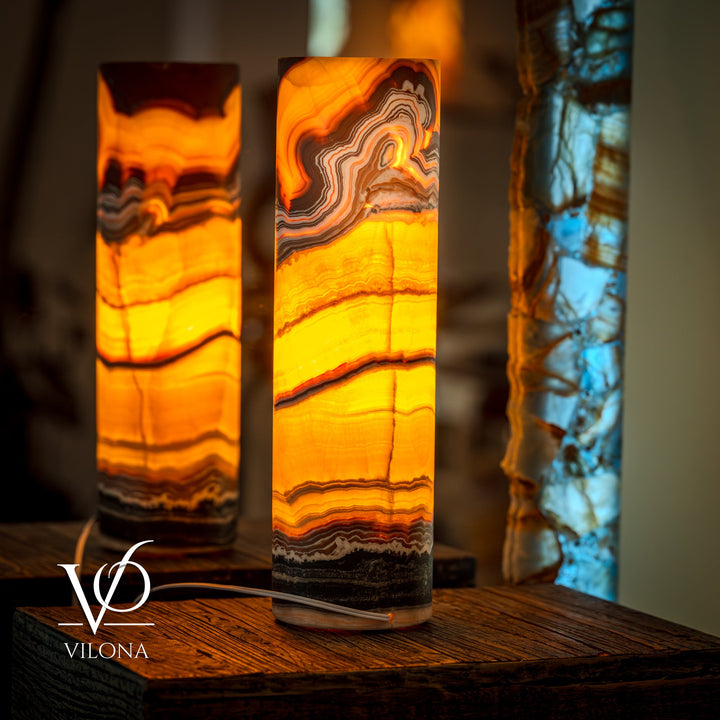 Pair of onyx cylinder table lamps with warm amber glow and wavy stone bands