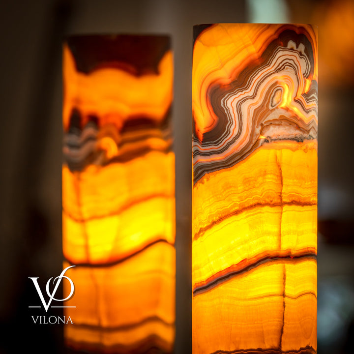 Close-up onyx cylinder table lamp glowing orange with concentric stone lines