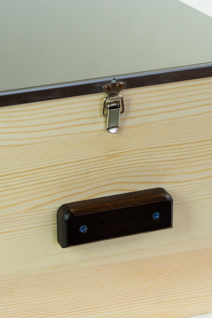 Light wood storage box lid latch and dark wooden handle detail