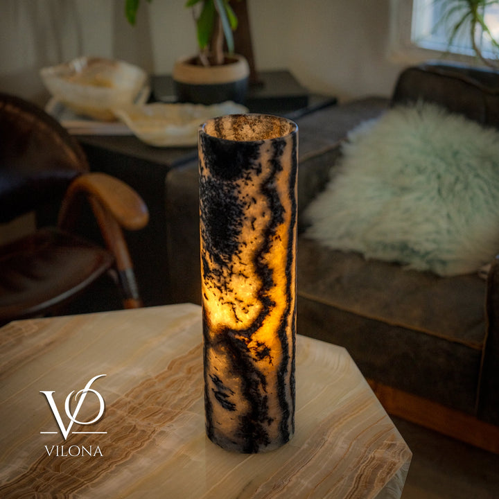 Onyx table lamp with tall cylindrical stone shade, dark swirls, warm light glowing through