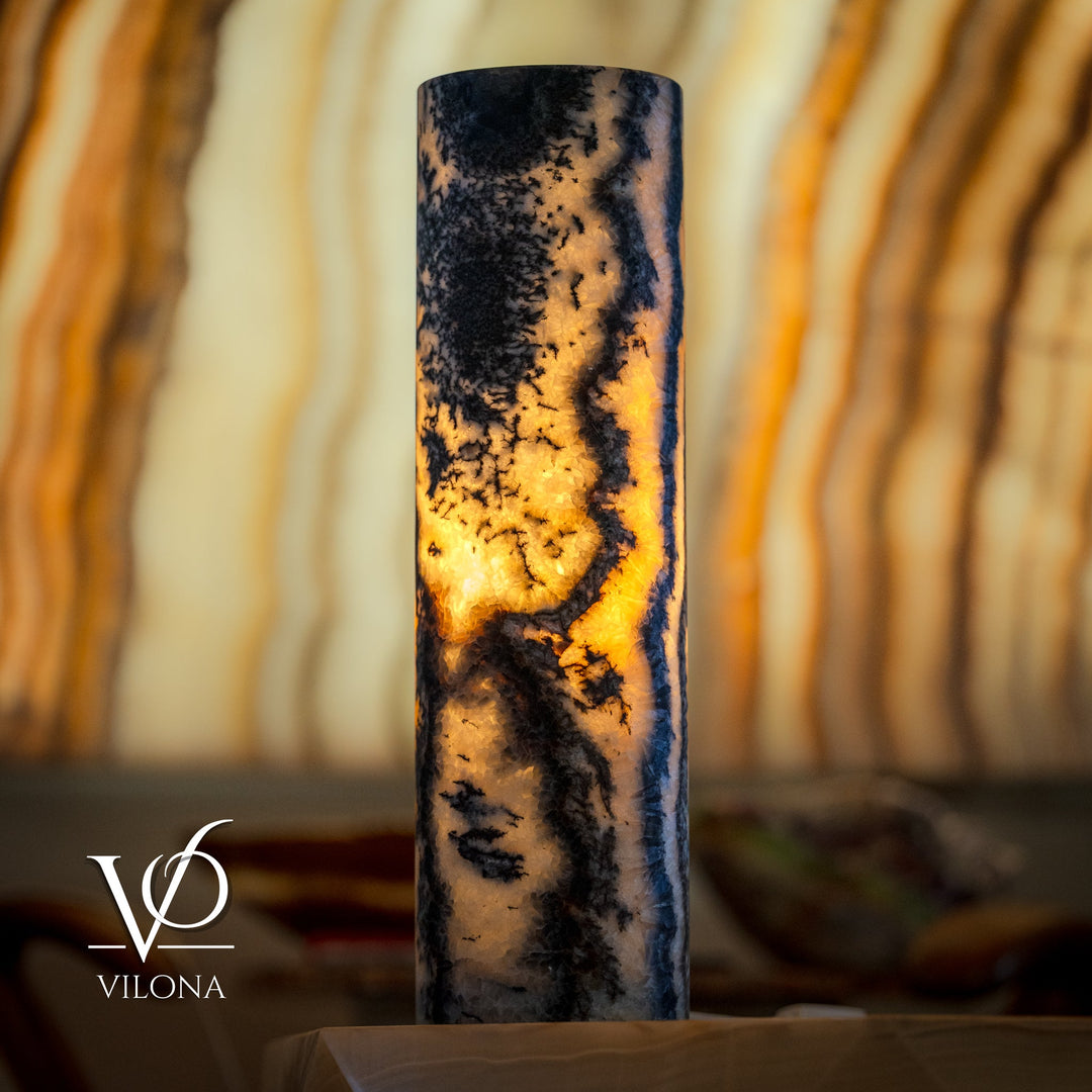 Close-up onyx table lamp cylinder with dark texture and bright amber glow from inside