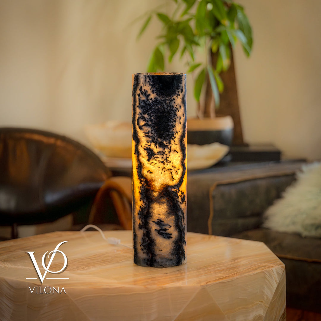 Onyx table lamp with tall cylindrical stone body, dark marbling and warm amber glow