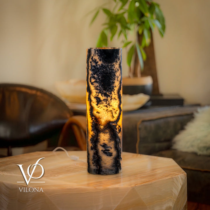 Onyx table lamp with tall cylindrical stone body, dark marbling and warm amber glow