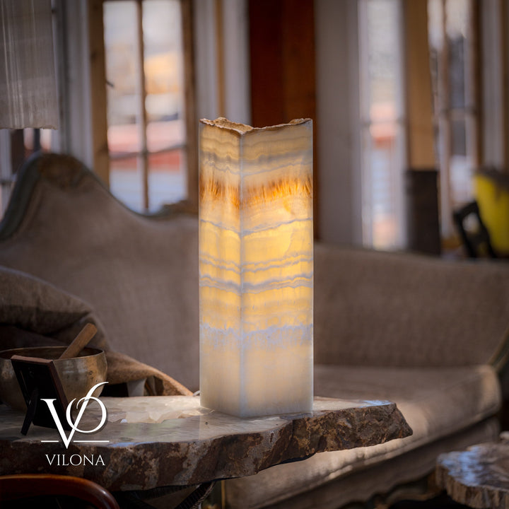 Square onyx table lamp with glowing cream shade and amber veining, on stone base