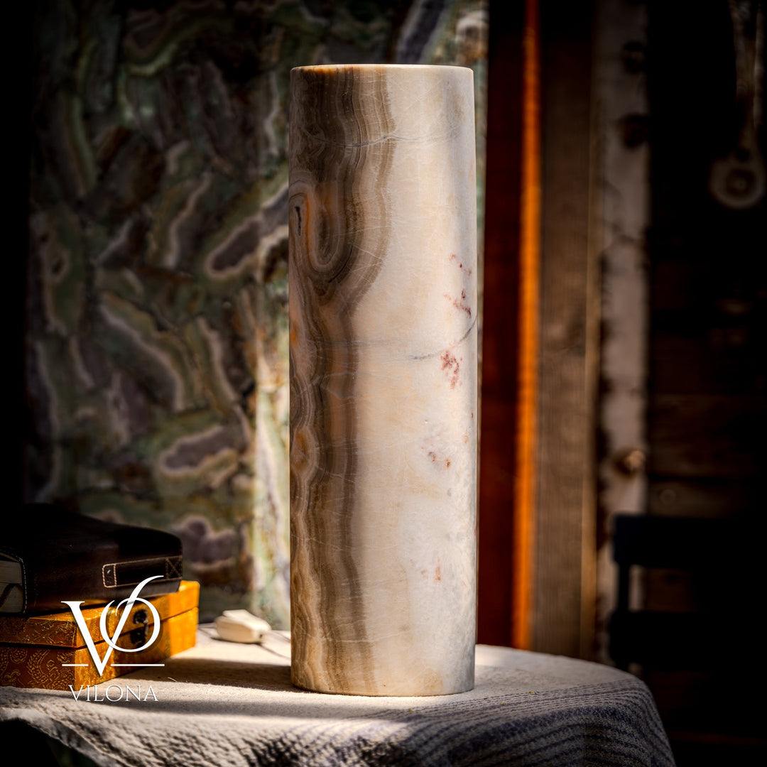 Cream cylindrical stone table lamp with vertical swirls and scattered specks; drum base visible.
