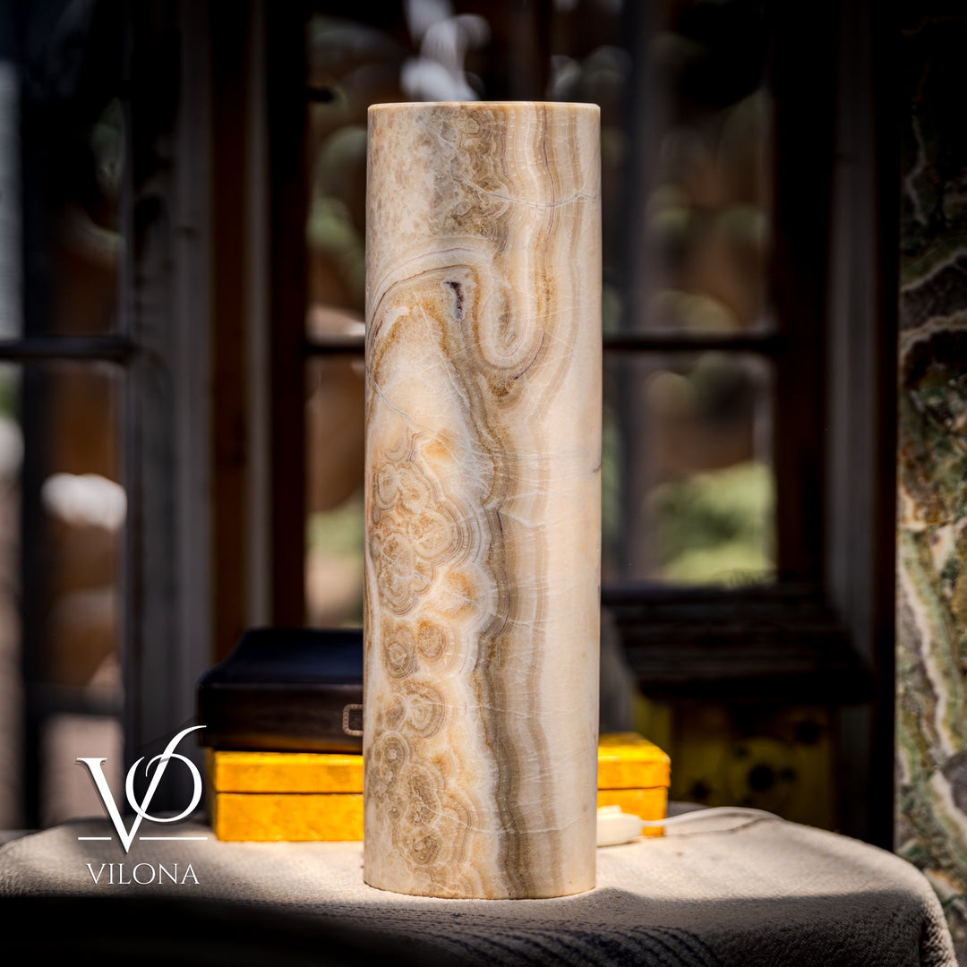 Standing cream cylindrical stone table lamp with prominent brown swirl patterns; tall silhouette.