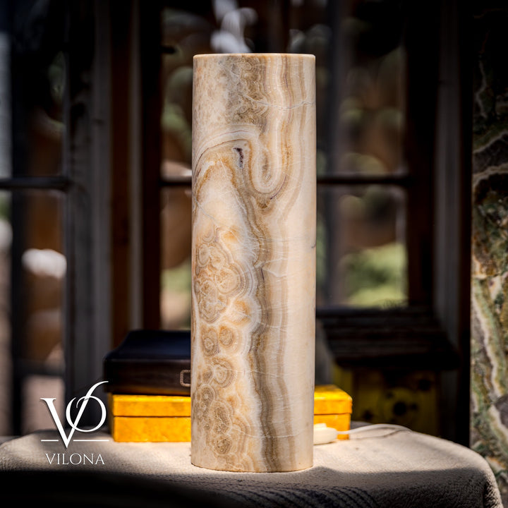 Standing cream cylindrical stone table lamp with prominent brown swirl patterns; tall silhouette.