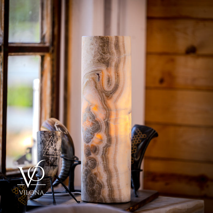Tall cylindrical stone table lamp in cream and brown with swirling veining; on/off not shown.