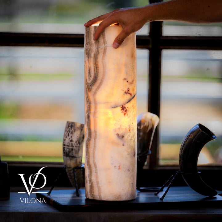 Close view of cream cylindrical stone table lamp; warm veining and small dark specks visible.