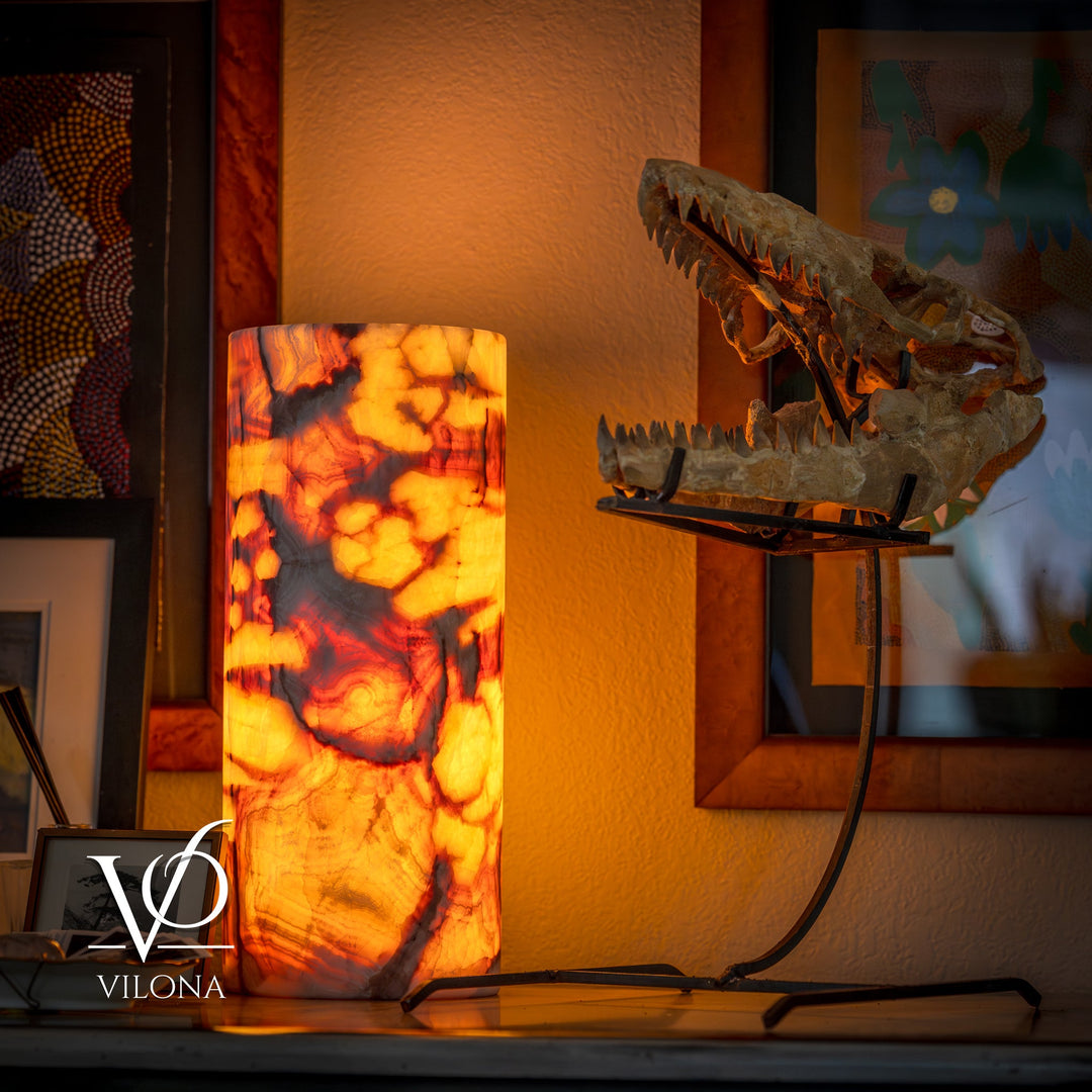 Table lamp with tall amber marbled cylinder shade and black wired base.