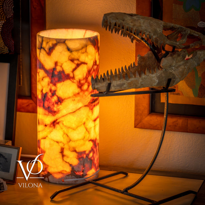 Table lamp with tall glowing amber marbled shade on black metal stand with cable.