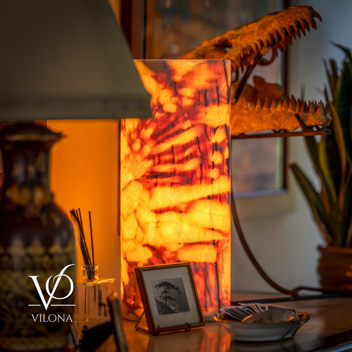 Tall table lamp with cylindrical amber onyx-pattern shade, glowing warm from inside