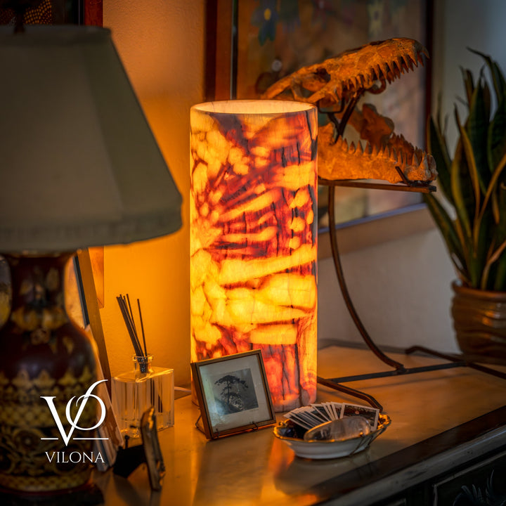 Table lamp with tall amber marbled drum shade glowing on a dark base.