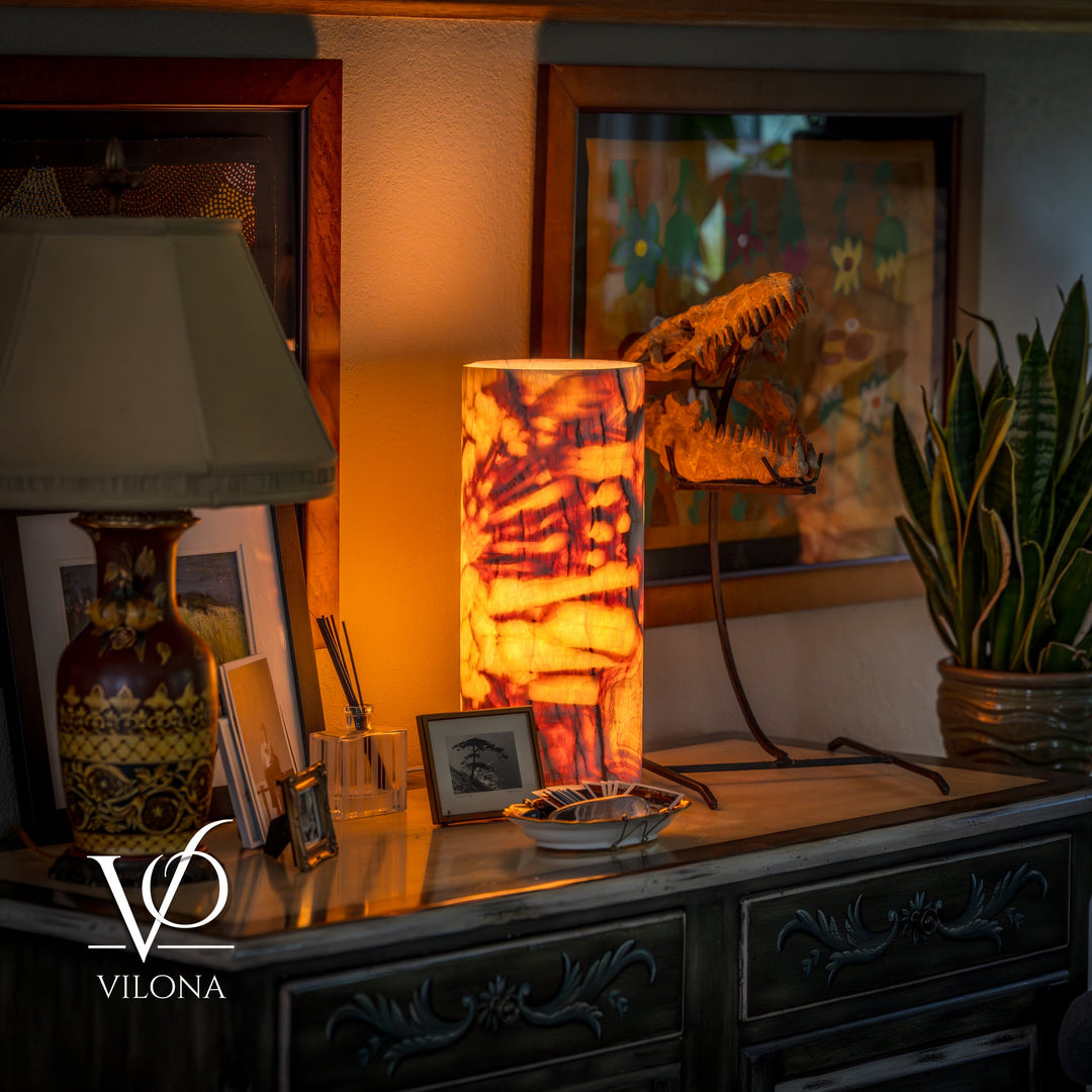 Table lamp with cylindrical amber marbled shade and dark metal tripod base.