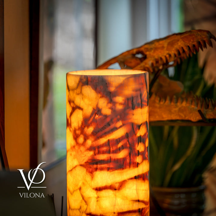 Table lamp with glowing cylindrical amber marbled shade, close-up view.