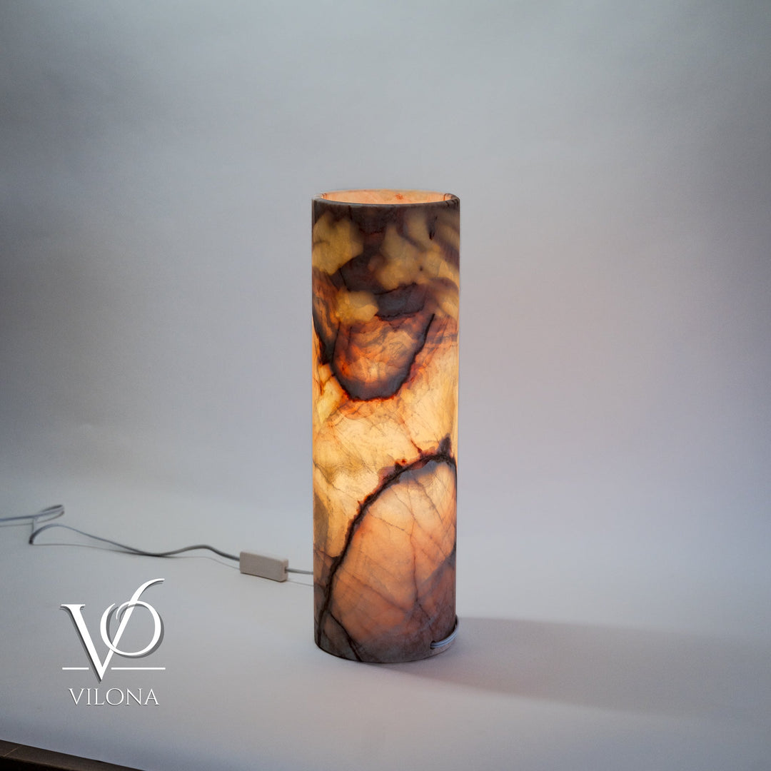 Cylindrical onyx-pattern table lamp with warm orange marbling and visible power cord