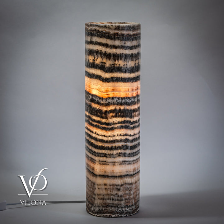 Cylindrical onyx table lamp base with black and cream striped design, warm illumination