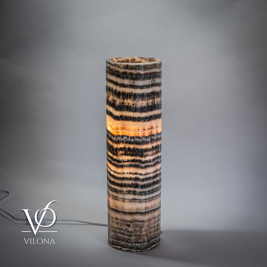 Cylindrical onyx table lamp base with horizontal black and cream bands, glowing center