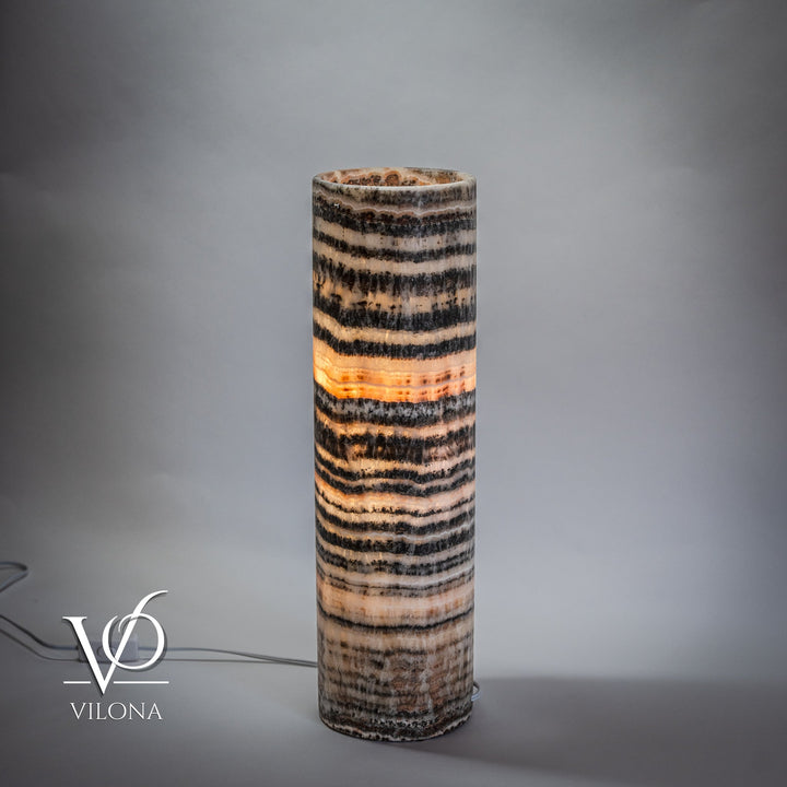 Cylindrical onyx table lamp base with horizontal black and cream bands, glowing center