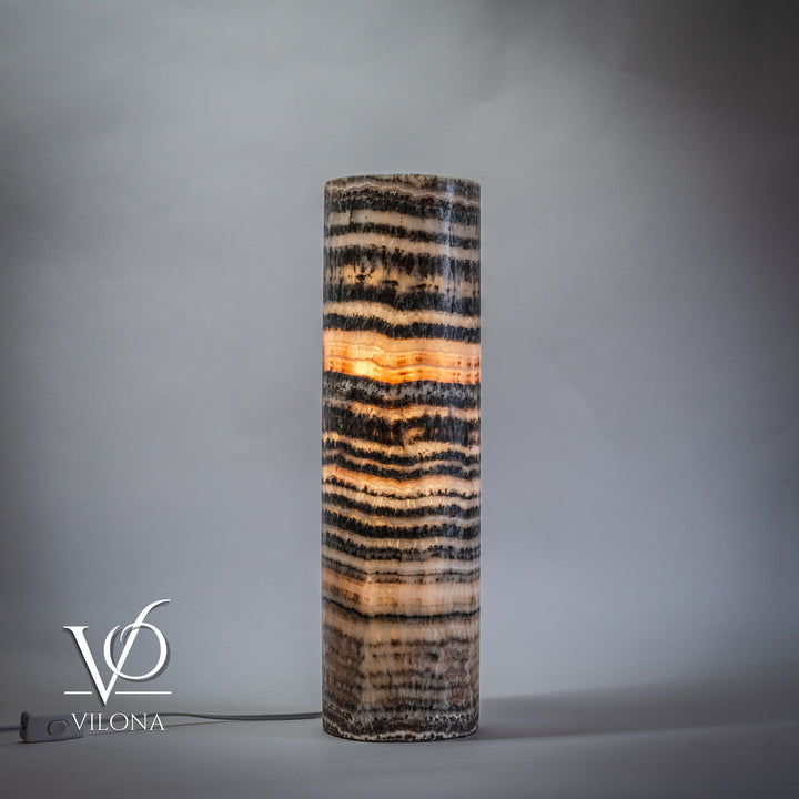 Tall onyx table lamp base with dark and light striped texture, warm light at center