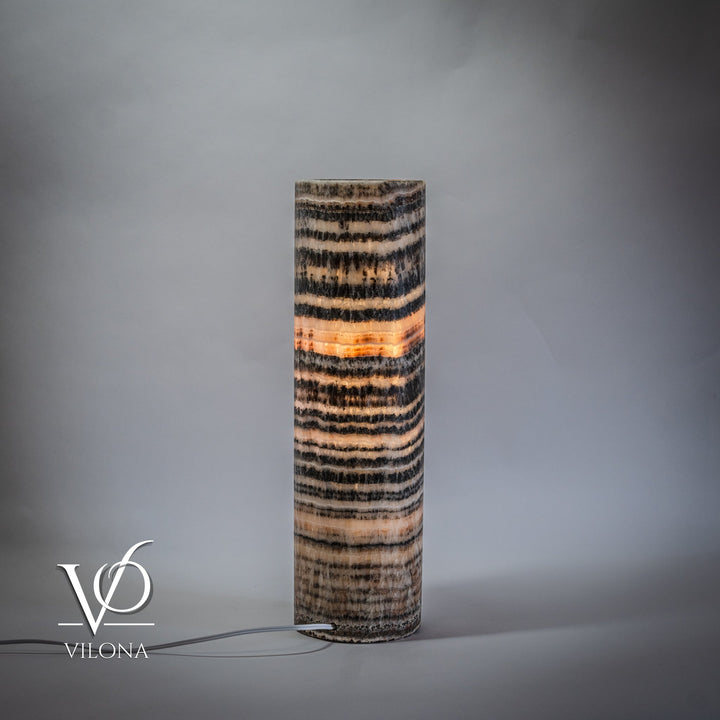 Cylindrical onyx table lamp base with black and cream striped pattern, warm glow