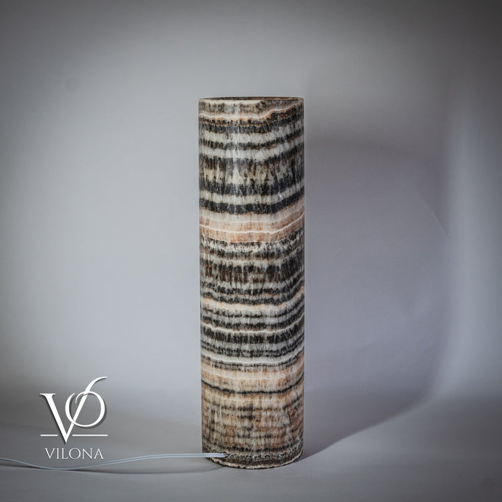 Tall cylindrical onyx table lamp base with wavy black and cream stripes, warm light
