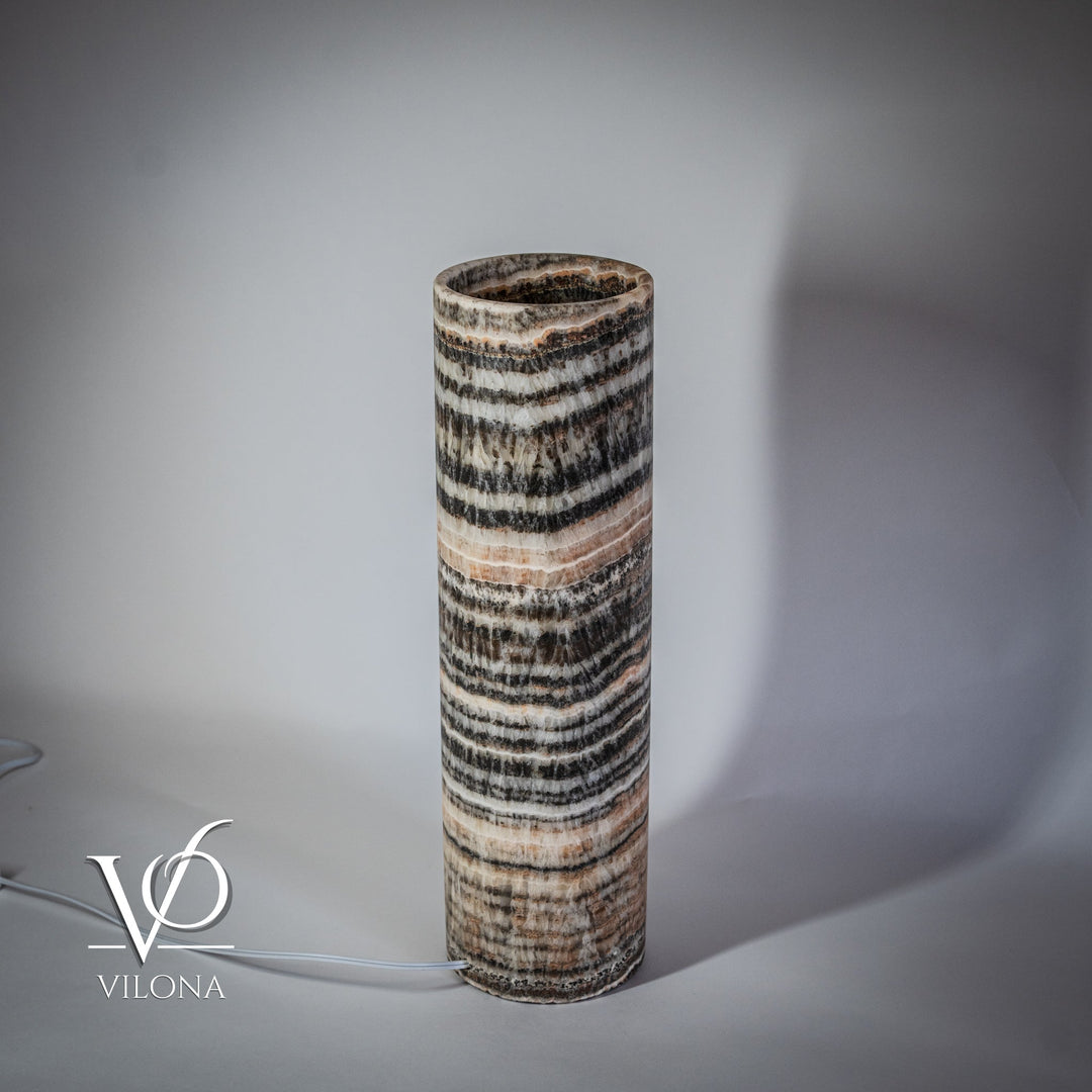 Cylindrical onyx table lamp base with dark-and-light wave stripes, warm light