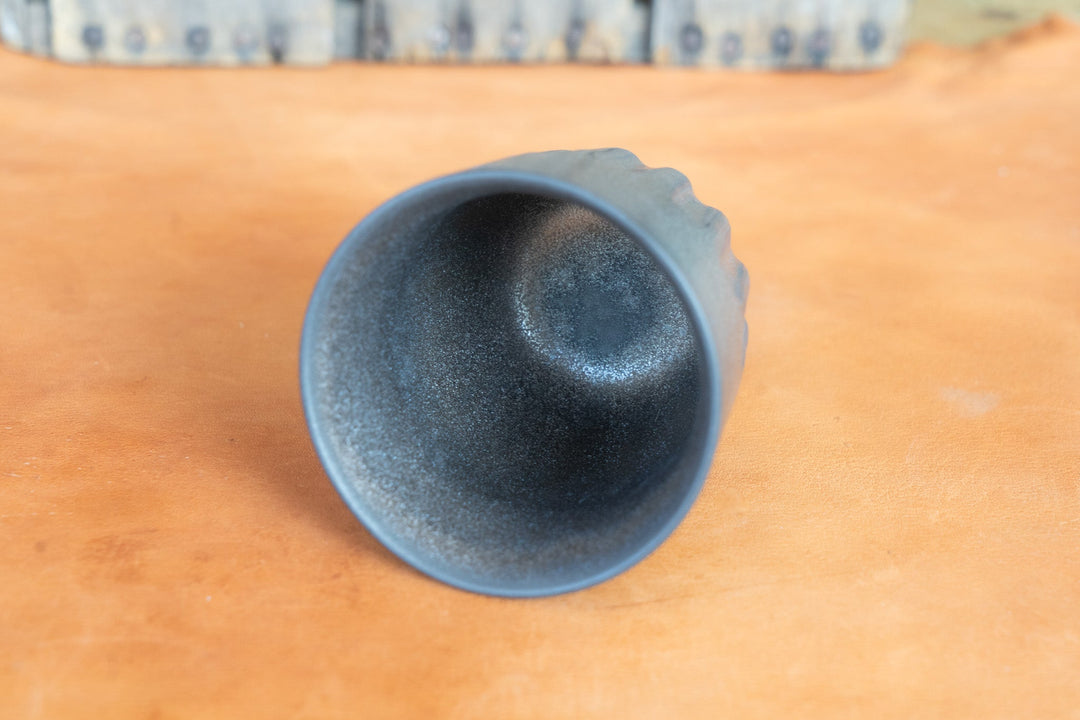 Bottom of metallic dark blue mug, smooth concave base