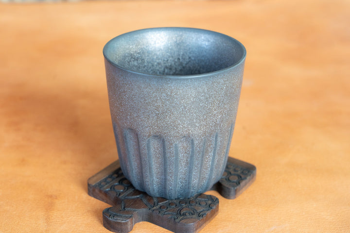 Metallic dark blue mug with fluted sides on decorative coaster