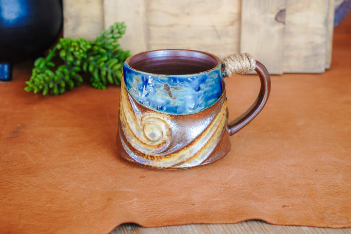 Rustic wave ceramic mug with blue interior and rope-wrapped handle