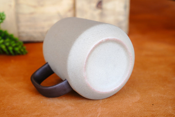 Two-tone ceramic mug shown from underside with dark handle and light interior