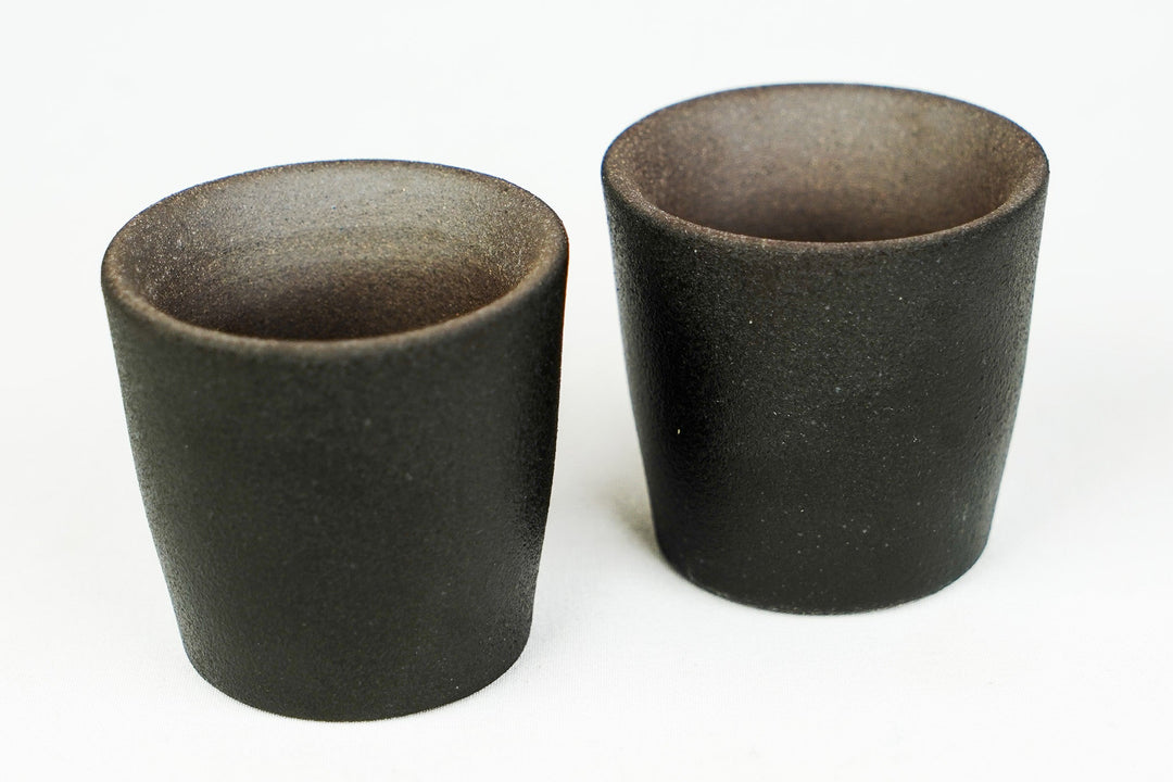 Pair of matte stoneware shot glasses in dark color with wide rims