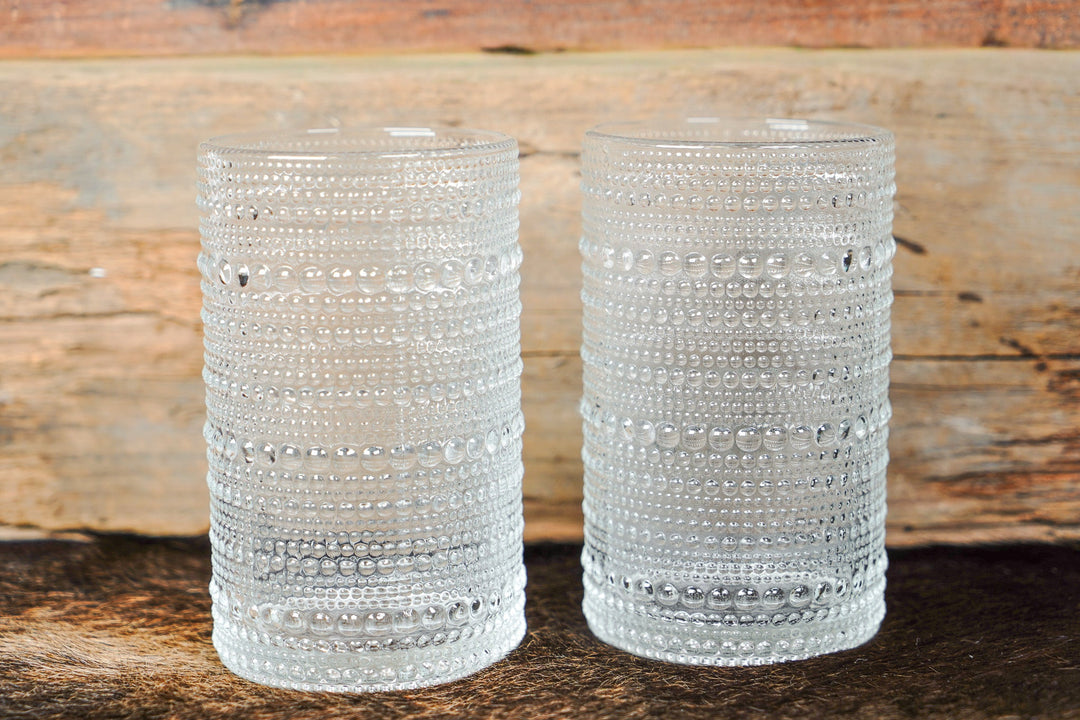 Pair of clear bubbled glass cylinder cups with raised bead texture and horizontal bands
