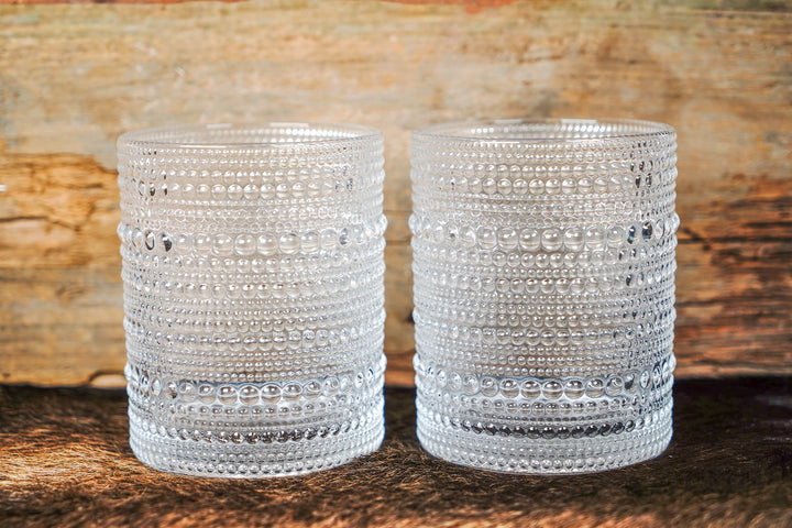 Two clear bubbled glass cups with horizontal bands of raised bead dots and textured sides
