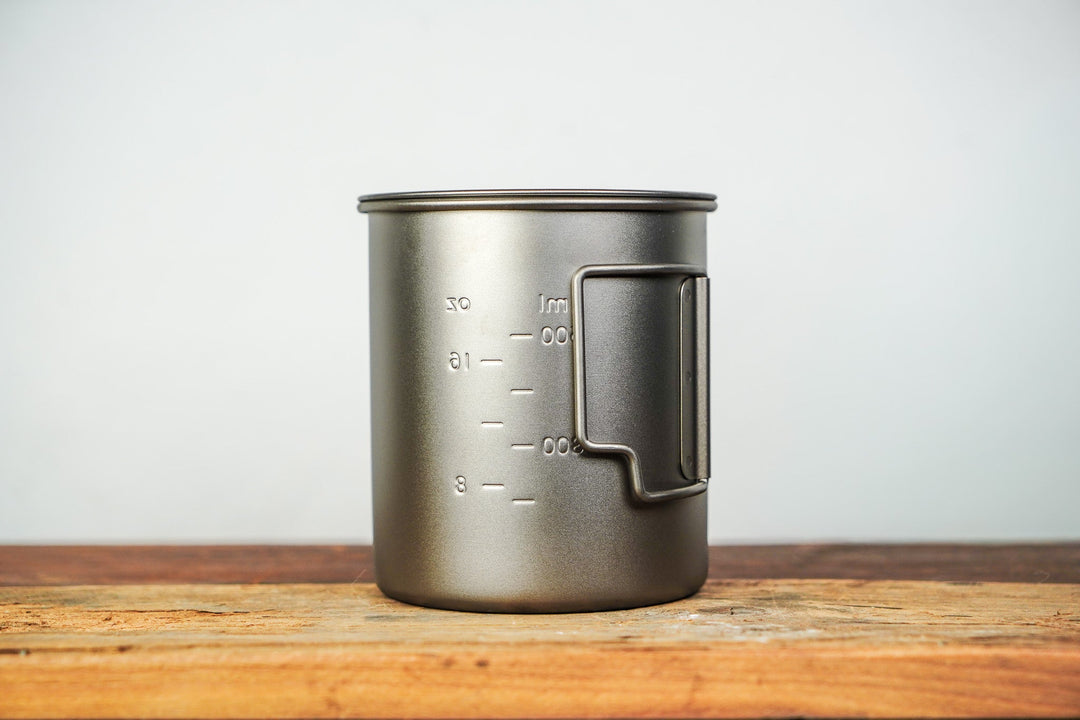 Metal camp cup with lid and side handle, volume measurement markings on the body