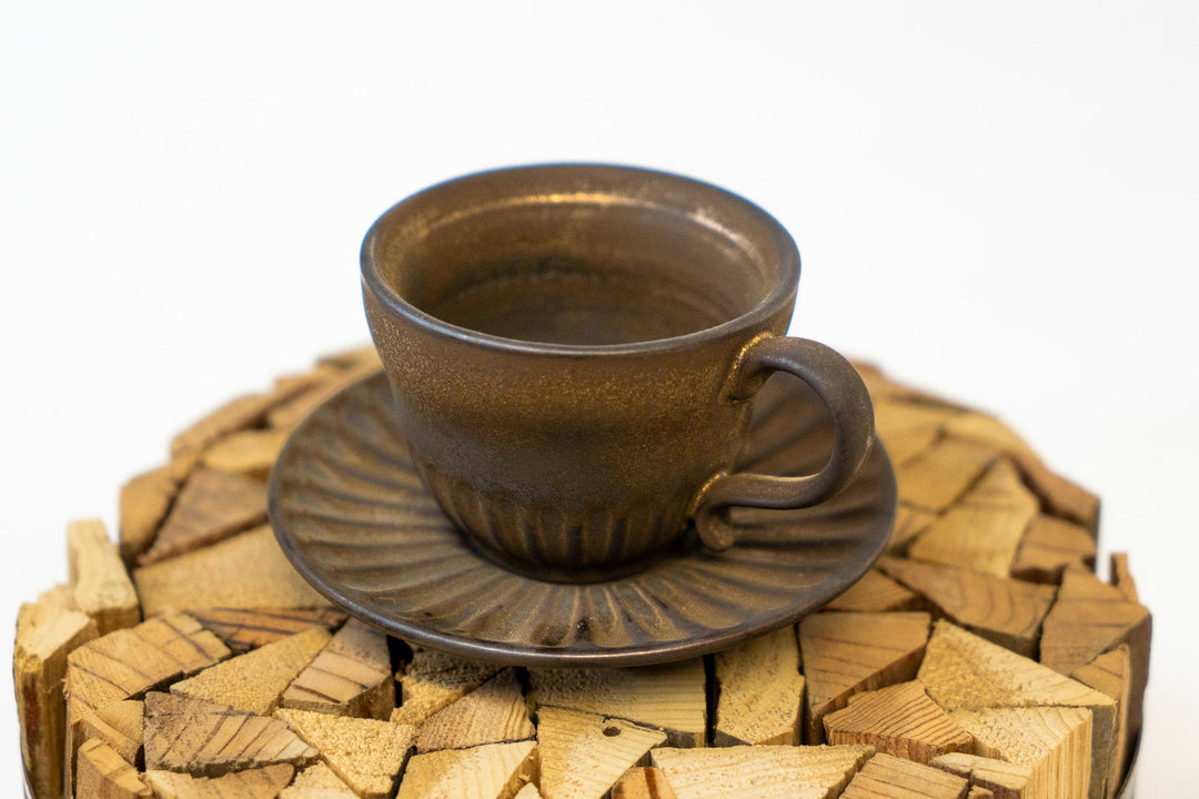 Close-up of dark brown espresso cup with handle on ribbed saucer