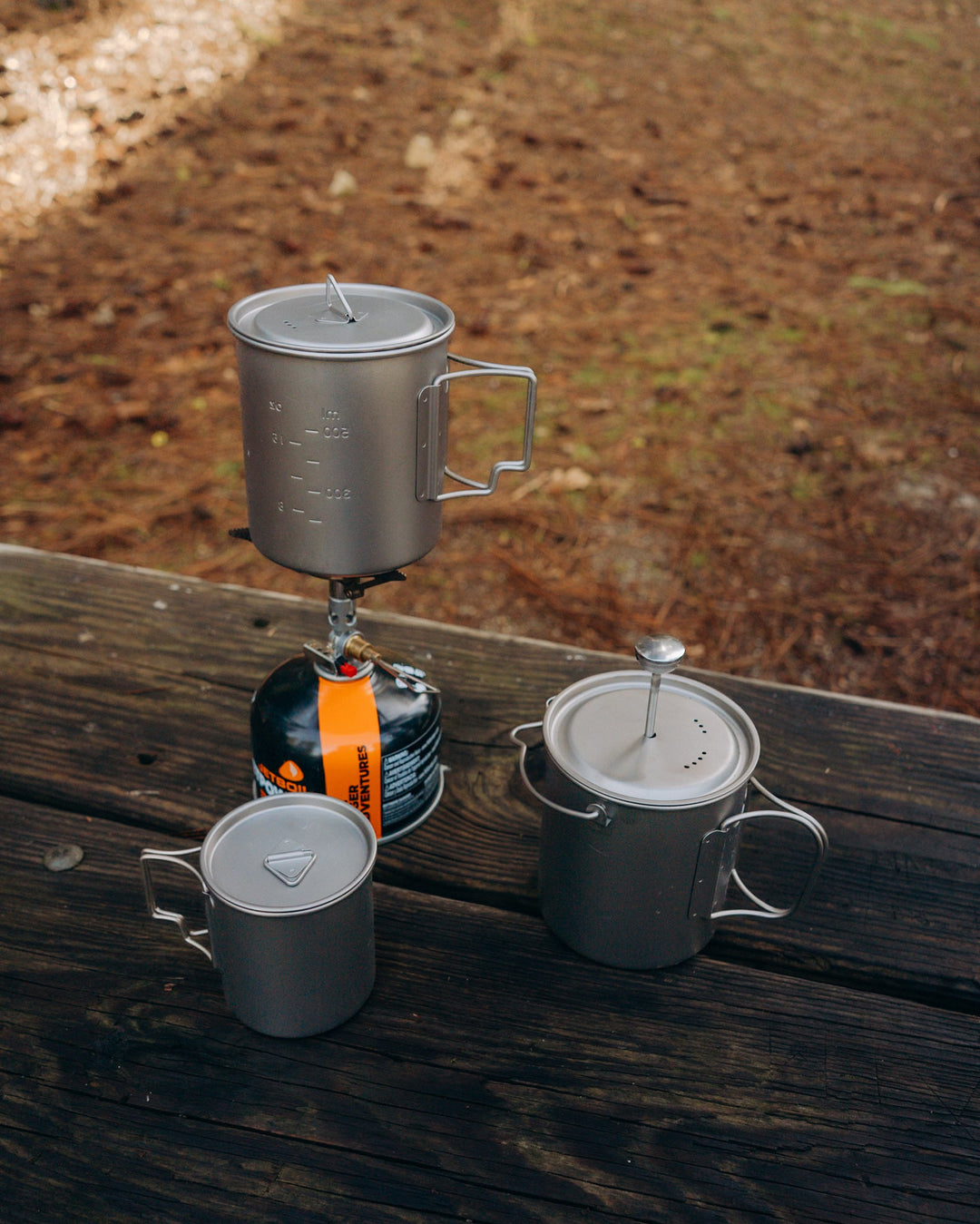 Gray metal camp cup with lid and side handle, with volume measurement markings