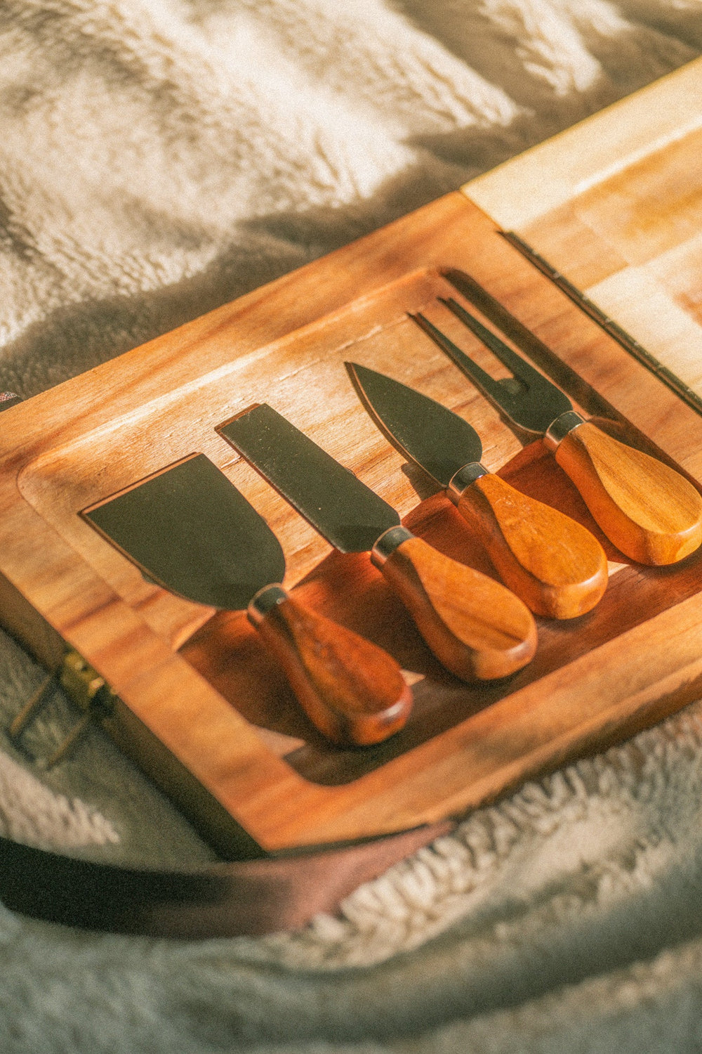 Wooden folding cheese board with engraved wine motif and dark webbing handles