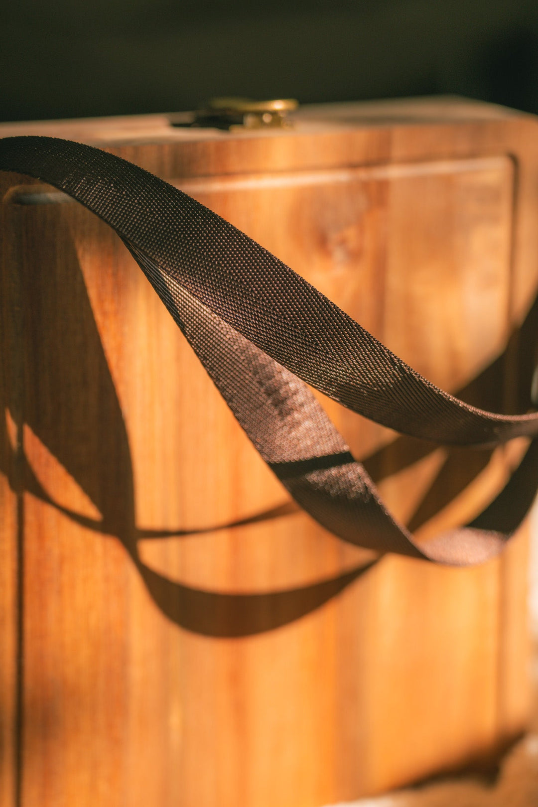 Close-up of dark webbing handles on a folding wooden cheese board