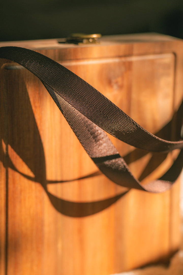 Close-up of dark webbing handles on a folding wooden cheese board