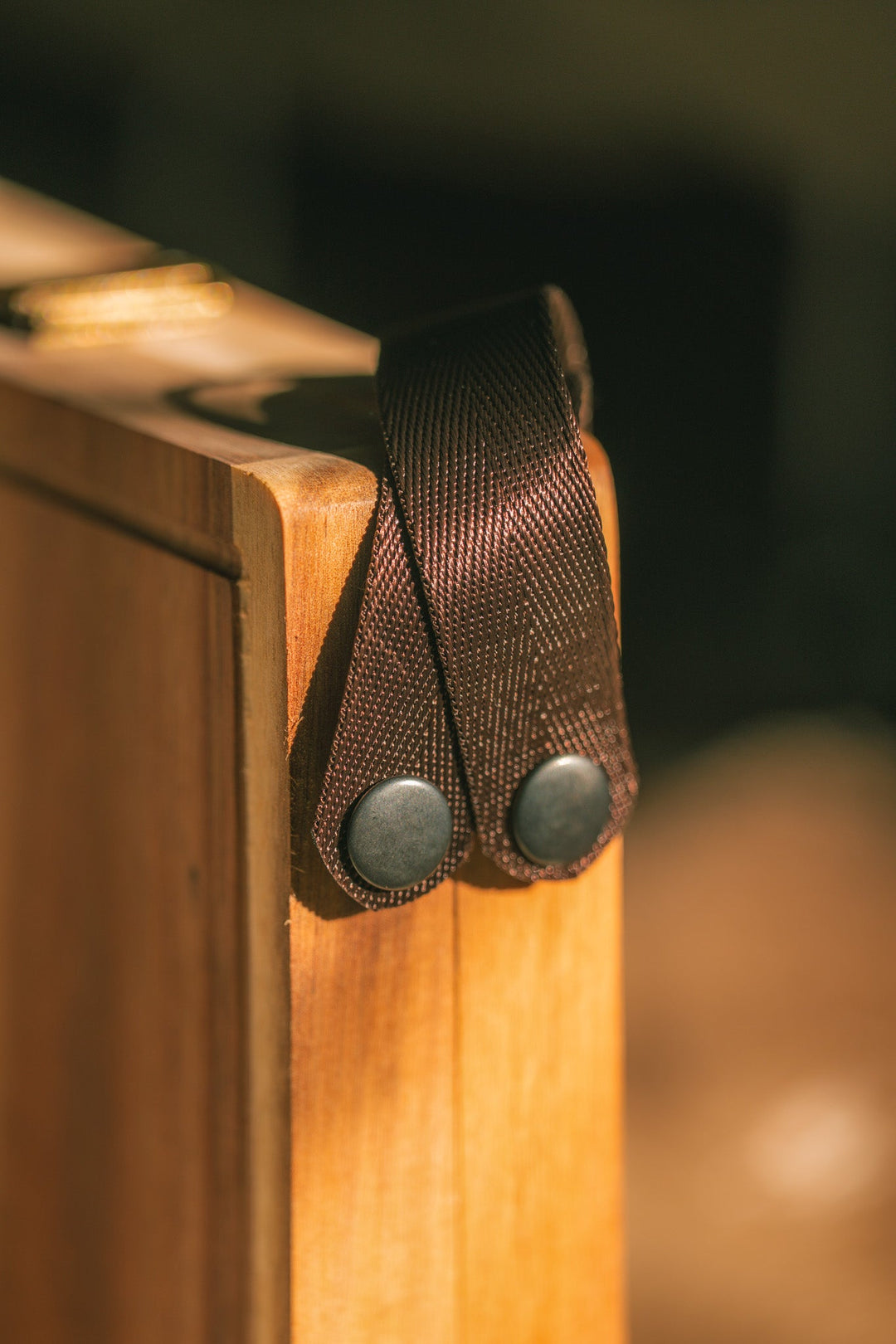 Dark webbing handle attached to a wooden folding cheese board corner