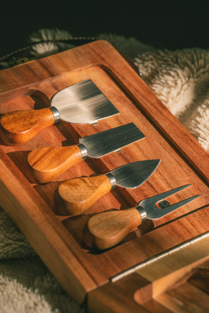 Wooden folding cheese board with cheese tools and dark webbing straps