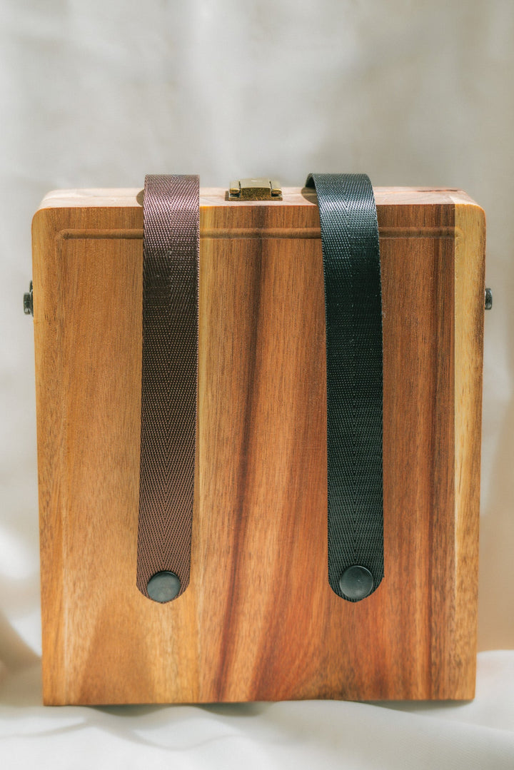 Folding wooden cheese board with two dark webbing straps and brass clasp